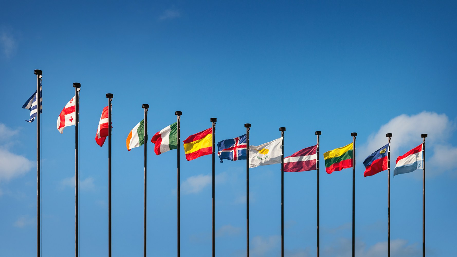 Foto von Flaggen von europäischen Ländern, die an Fahnenstangen im Wind wehen