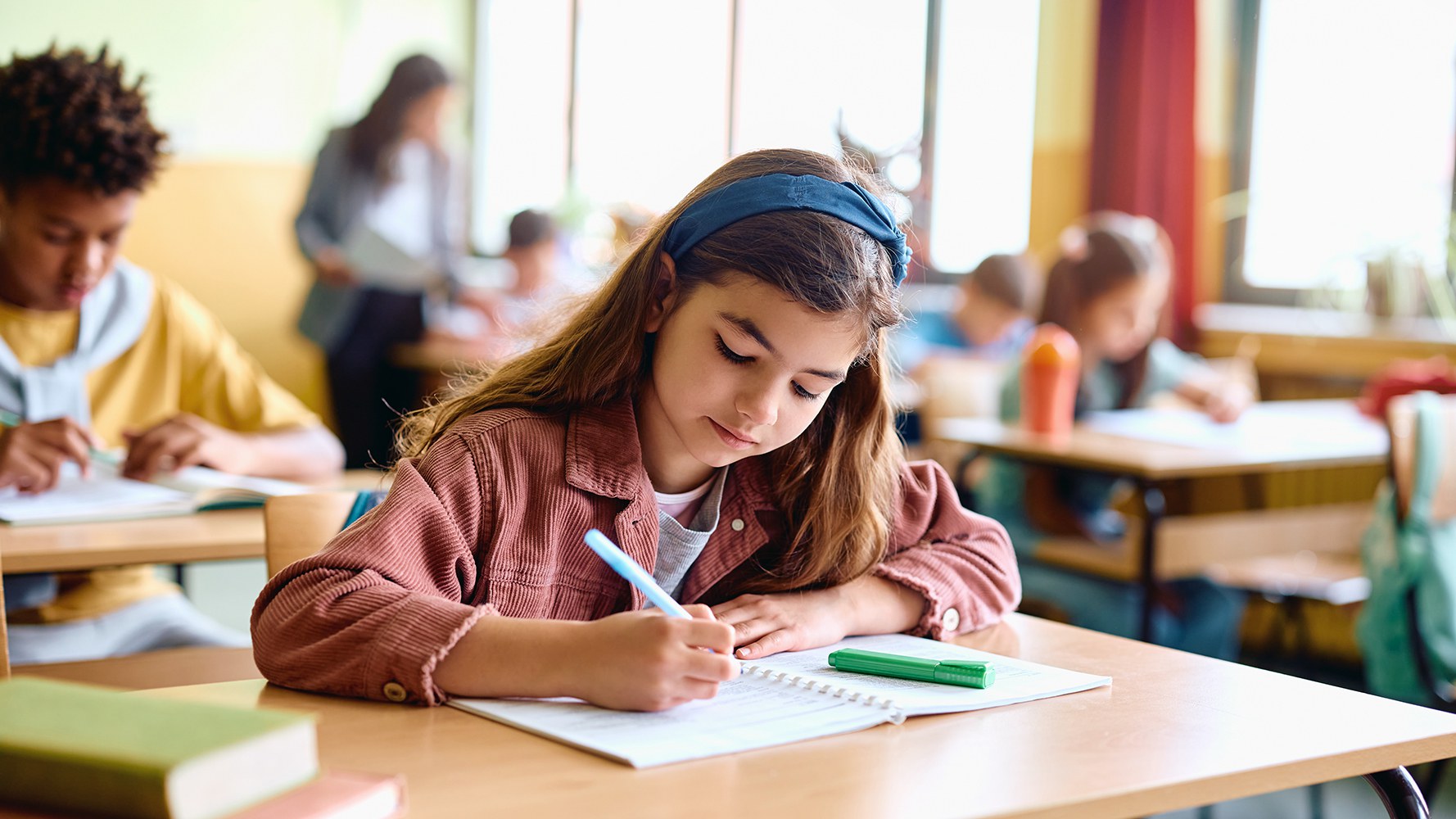 Une fillette écrit quelque chose dans un cahier à l'école