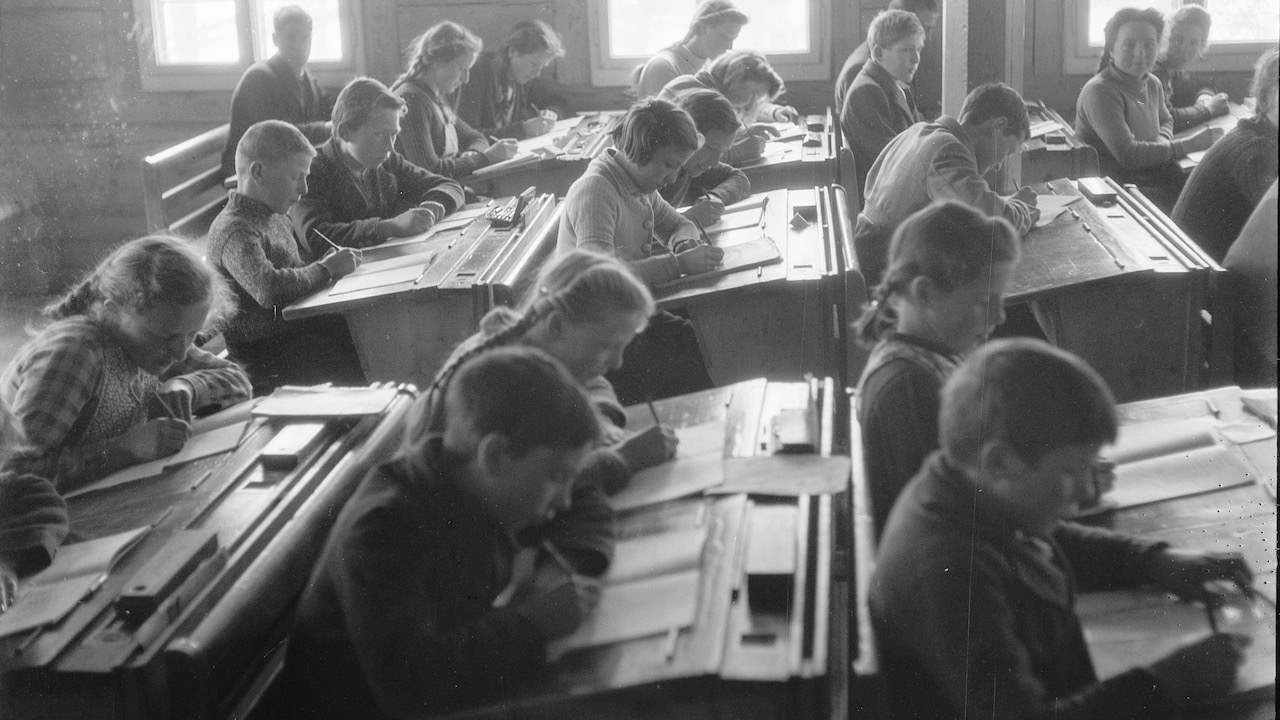 On voit une salle de classe vers 1942, les élèves sont assis en rang.