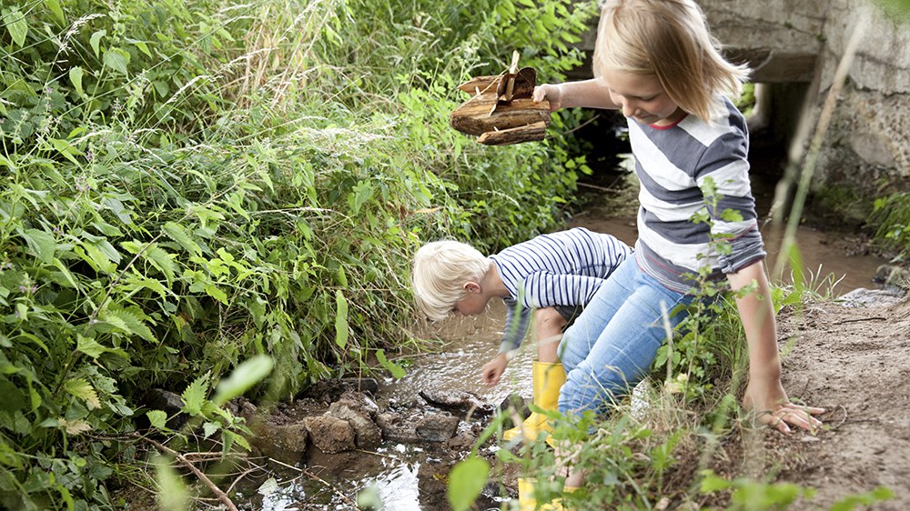 Deux enfants jouent au bord d'un ruisseau